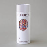 Fleuryx wildflower seed shaker packaging with colorful seeds visible through a window on a gray background