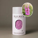 Fleuryx Lemon Beebalm (Monarda citriodora) Native Wildflower Seeds in a white seed shaker with a striped lid, showing purple colorful coated wildflower seeds and a photo of Lemon Beebalm flowers.